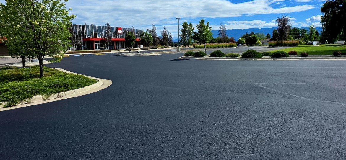 Finished black asphalt drive aisle and parking area along a commercial building frontage.