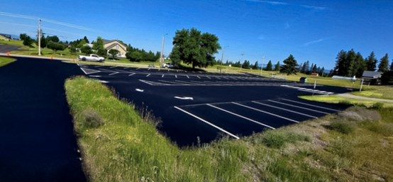 Fresh white stall lines running along a newly coated black asphalt parking area.