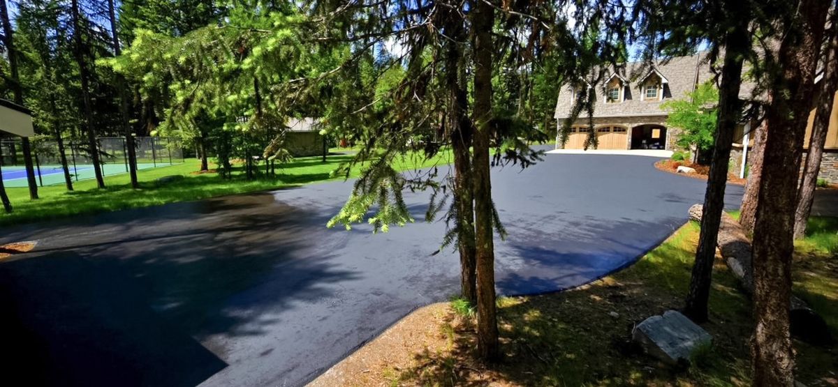 Finished coated driveway and turnaround area on a wooded residential property.