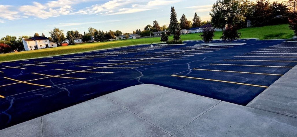 Freshly sealed and striped asphalt parking lot photographed in low evening light.