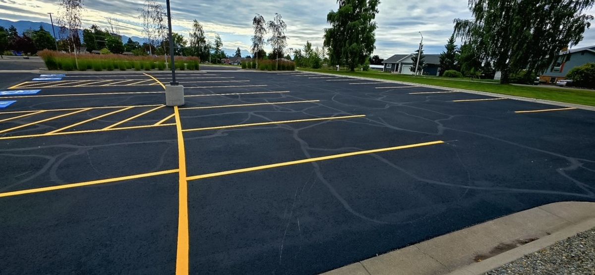 Yellow stall and drive-aisle lines running across a large freshly sealed parking area.