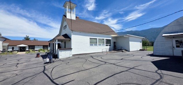 Sealer hose lines laid out across an asphalt parking lot in front of a white building with a steeple.